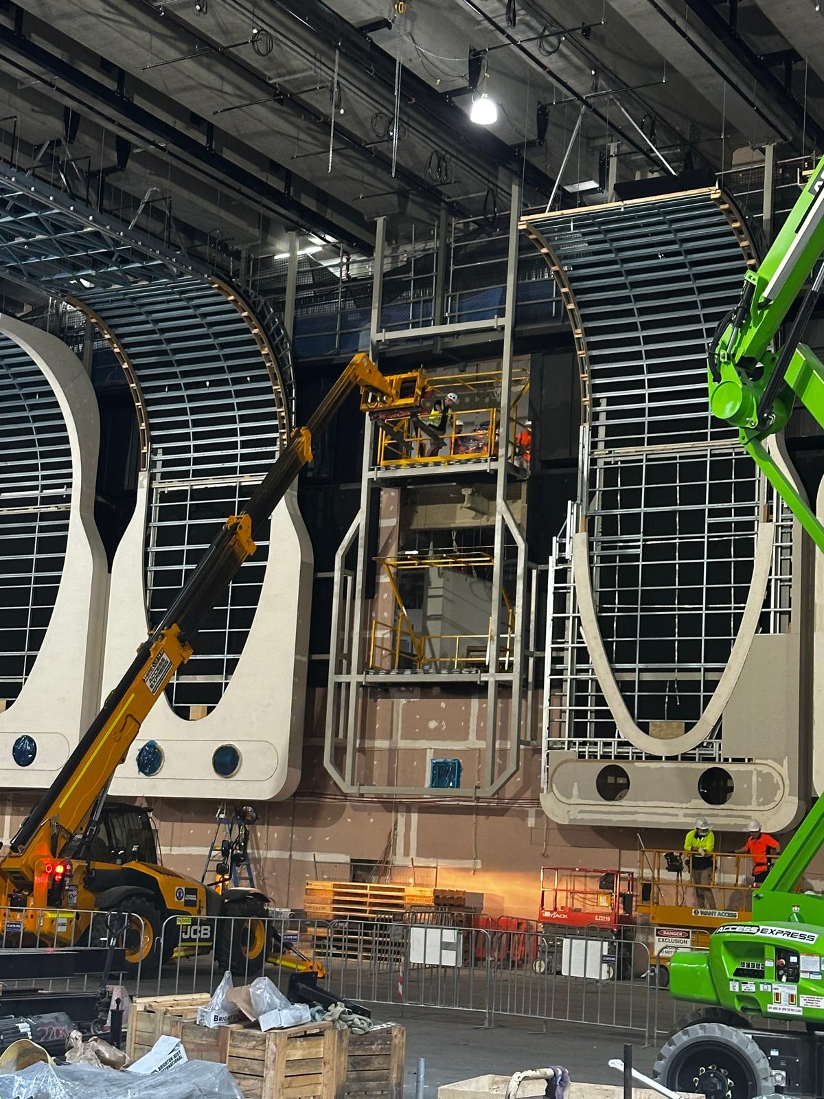 Construction of curved structures with workers on lifts.