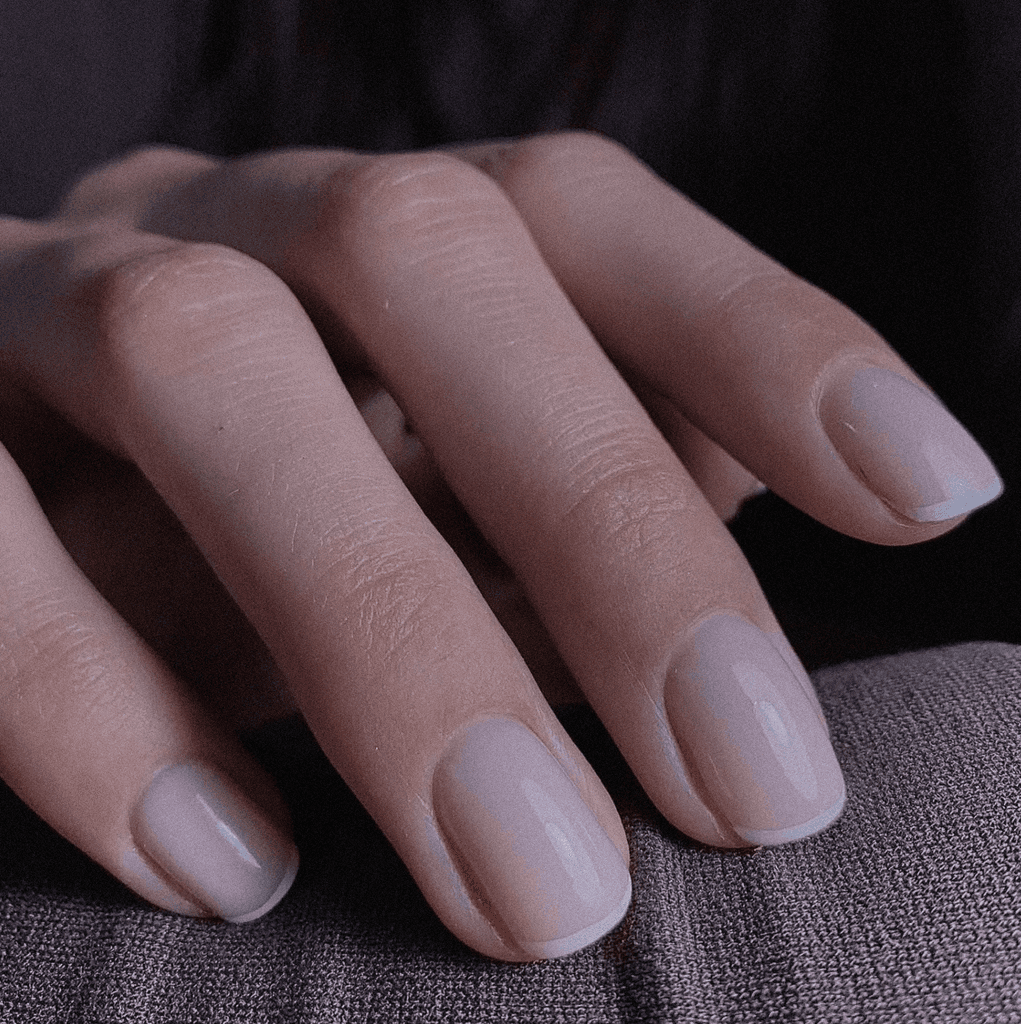 Hand with nude and glittery rhinestone nails in a sweater