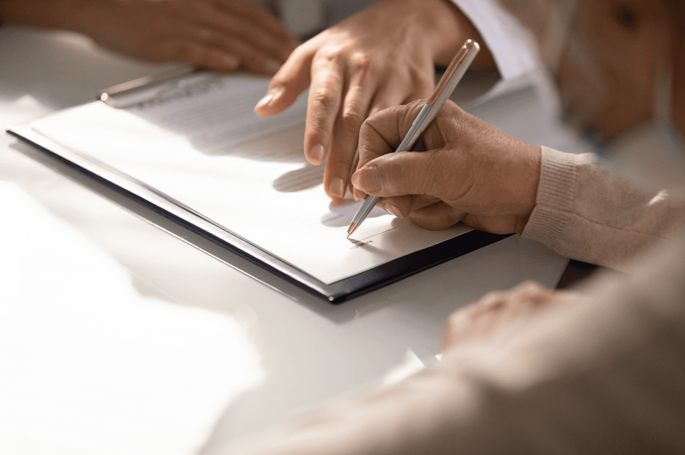 Close up of aged woman patient hand signing medical insurance contract at doctor office