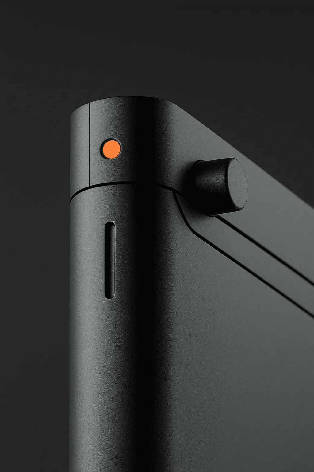 Close up of black device corner with orange button and side knob