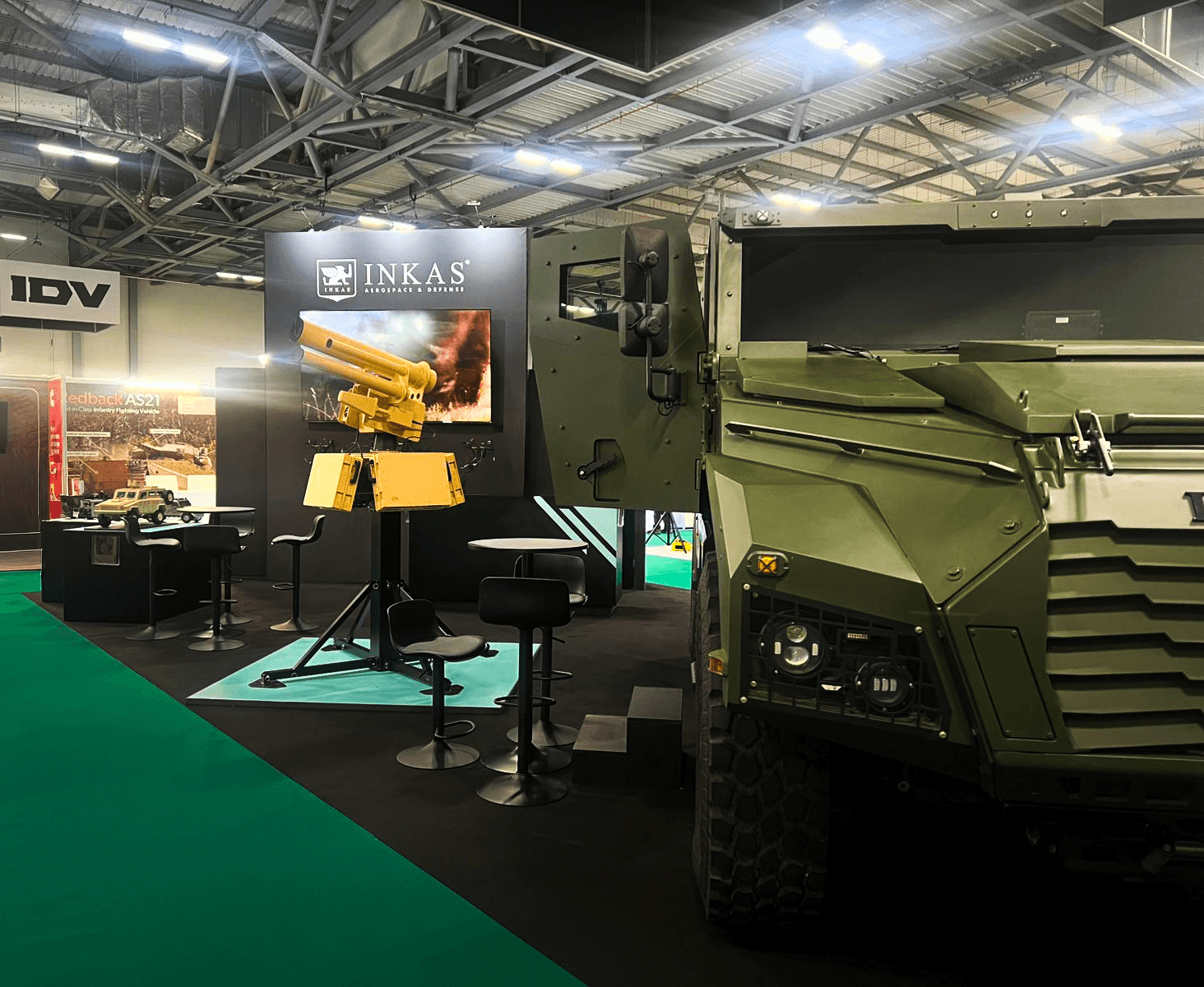 Stand INKAS Armored Farnborough 2026 par Expace – vue latérale avec véhicule tactique blindé exposé, éclairage ciblé et aménagement stand défense sur-mesure