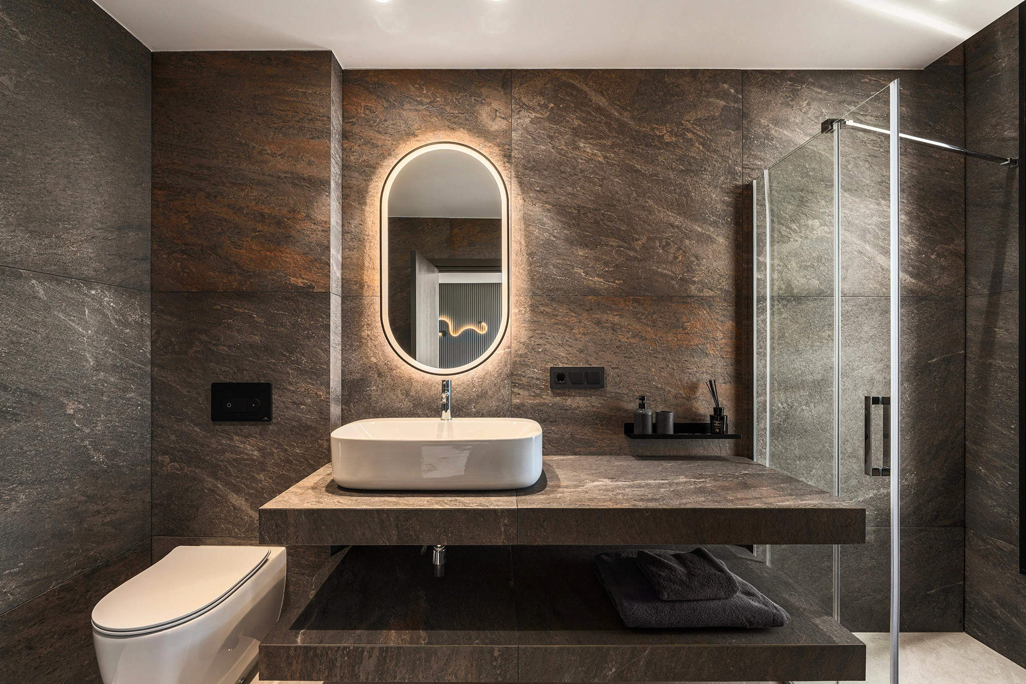 Villa Vista Marbella bathroom with stone-clad walls, floating vanity, and illuminated oval mirror