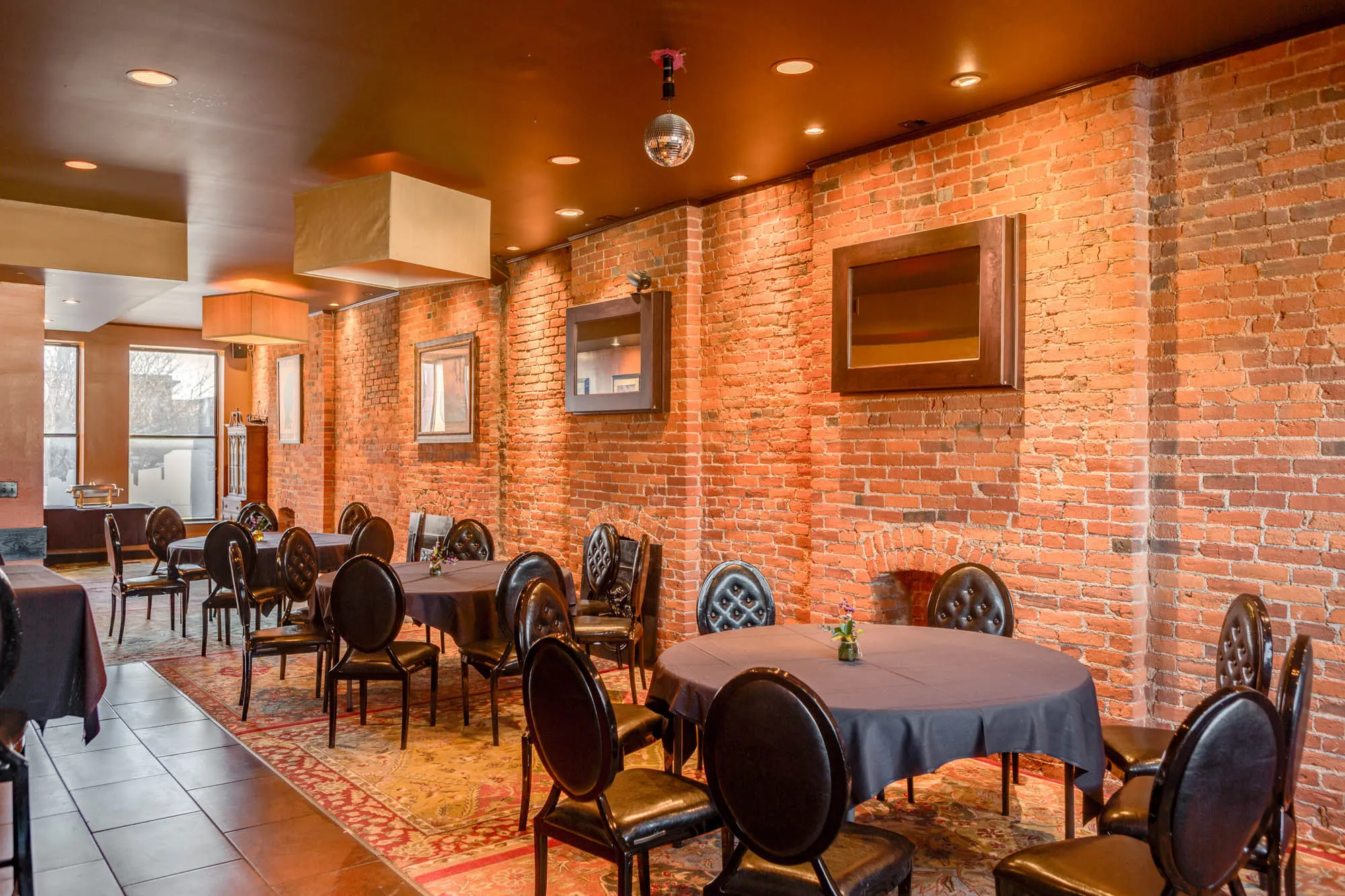 Round tables with black linens along a brick wall at Sidebar