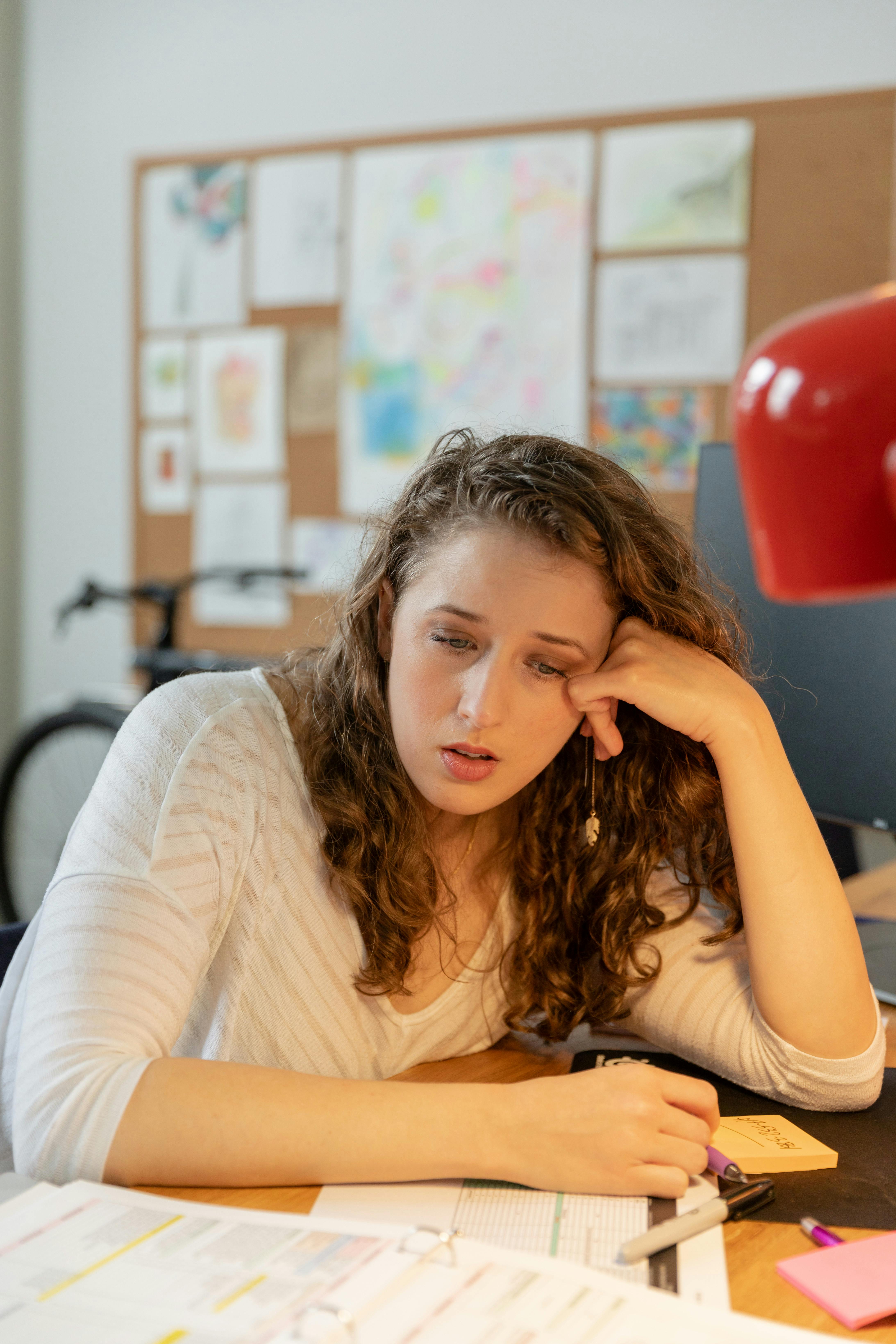 Ragazza stanca alla scrivania tra scadenze e appunti: ansia da studio/lavoro, gestione del tempo