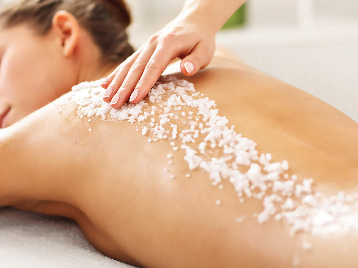 A client receiving a hot stone massage, with smooth black stones placed along their back. The warm lighting enhances the soothing and therapeutic atmosphere.