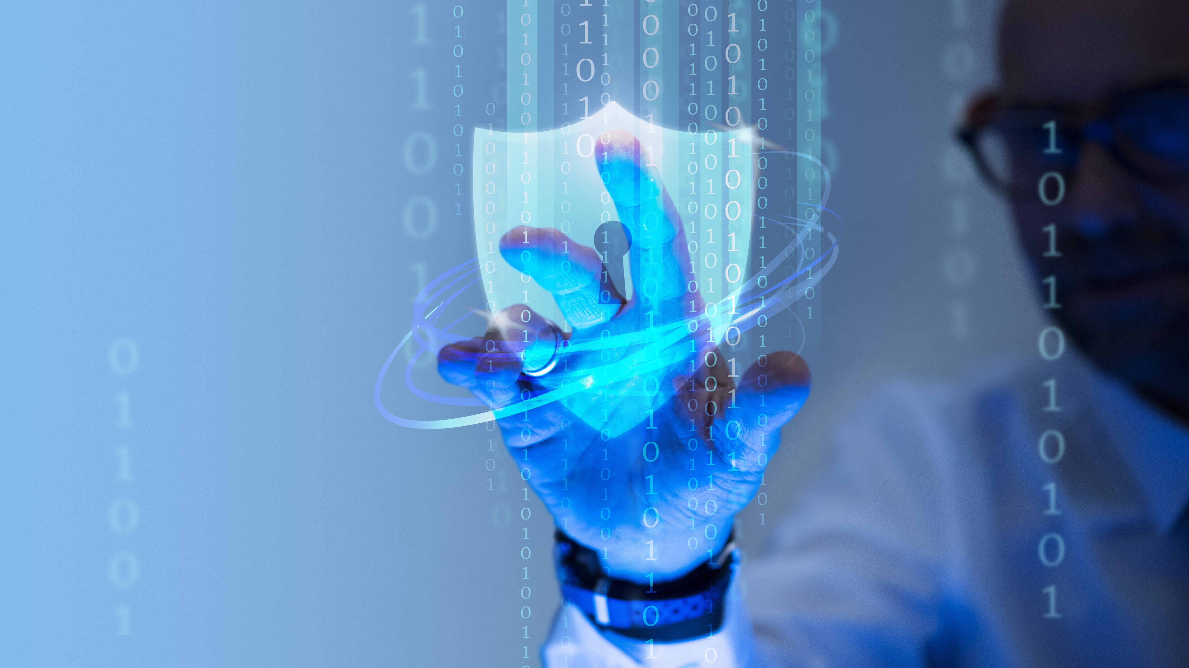Cybersecurity concept showing a hand touching a glowing blue holographic shield icon amidst streams of binary code, representing data protection, network security, and antivirus software.