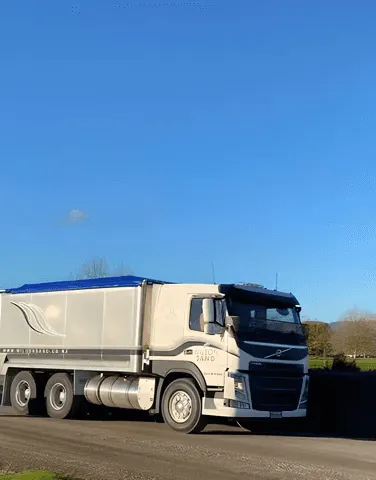 A large semi-truck and trailer driving up a farm race