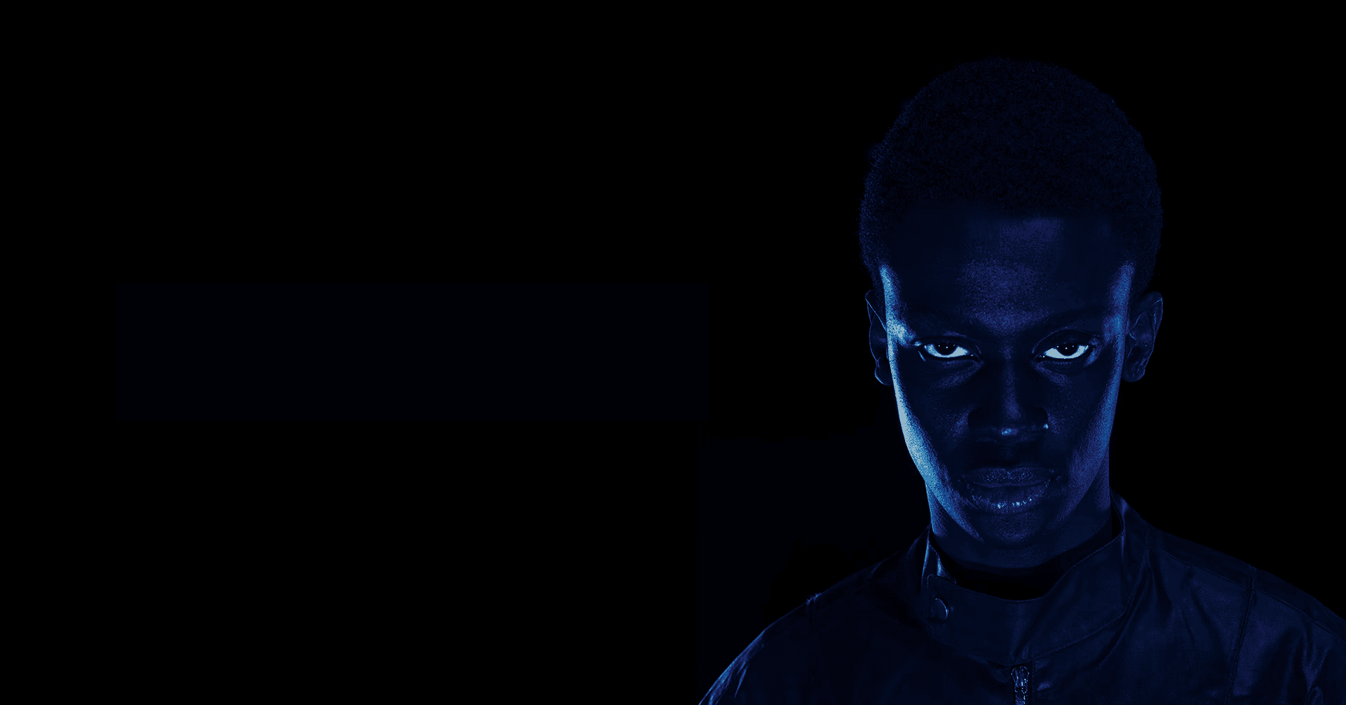 Man wearing baseball hat and beige hoodie sitting on leather couch