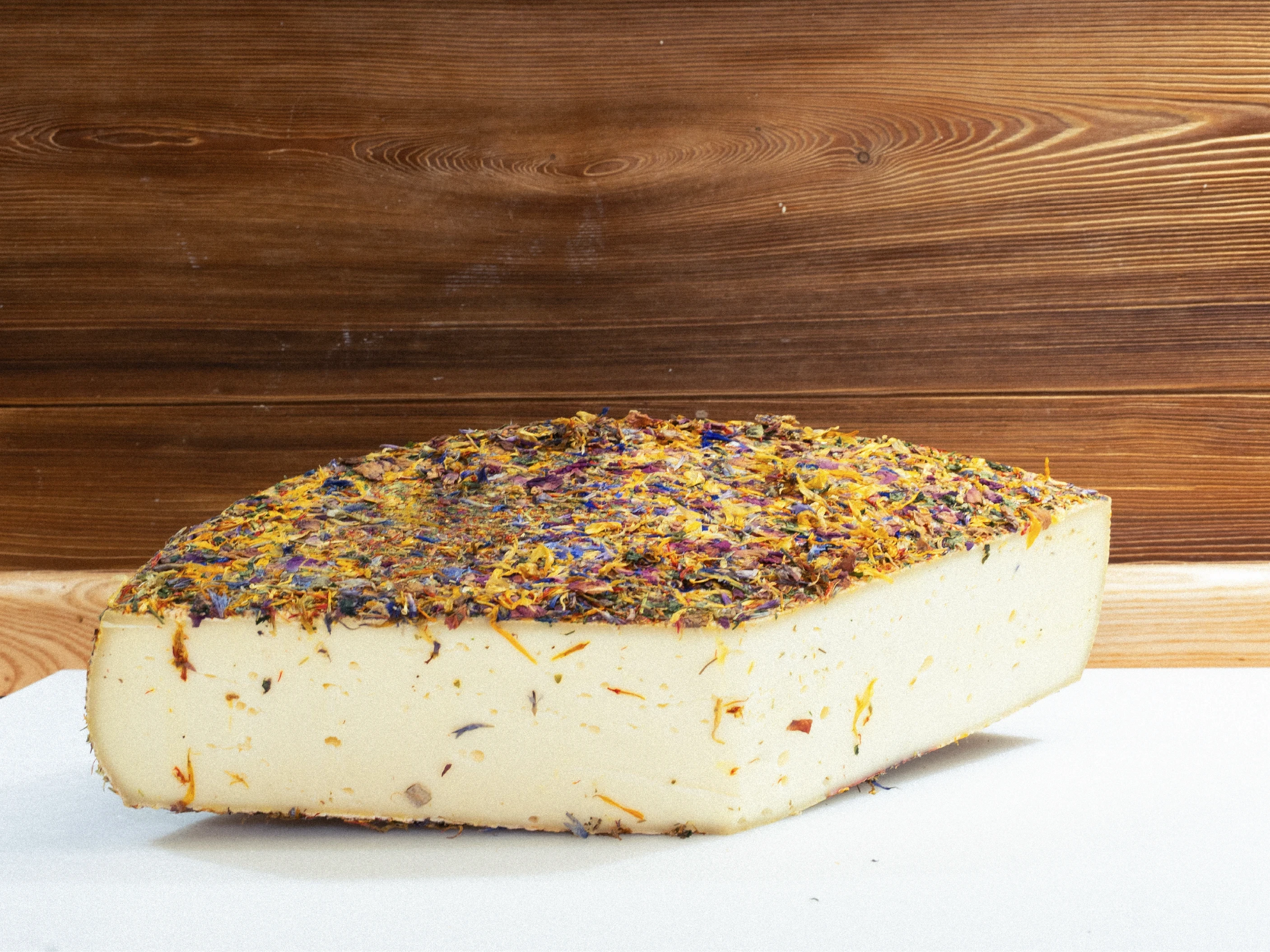 Morceau de fromage garni de fleurs sur une table en bois