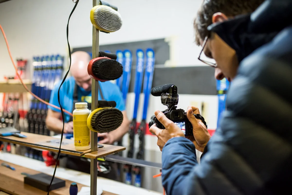 Technicien préparant une paire de skis dans un atelier Salomon, affûtage et fartage en gros plan.