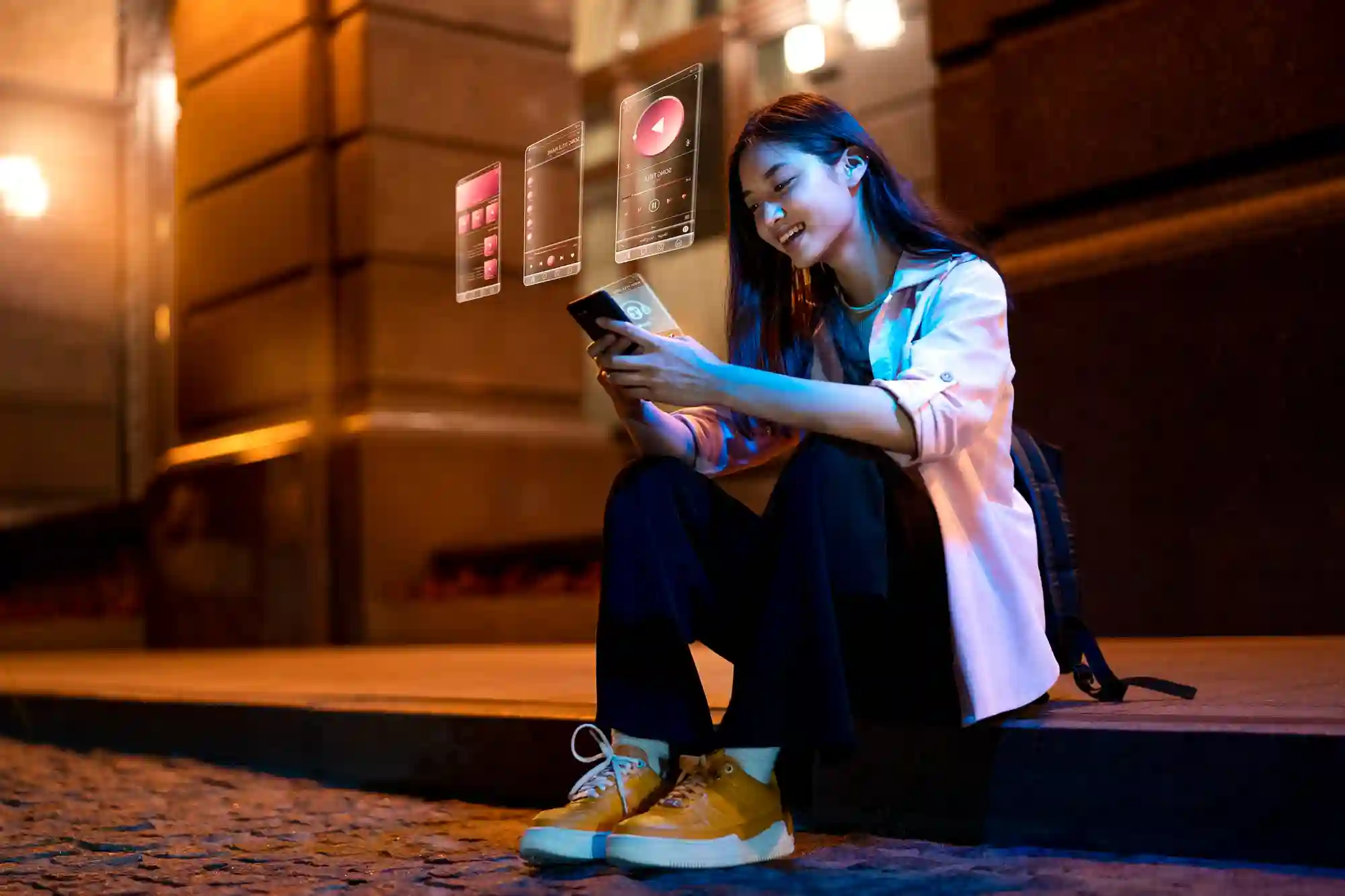 A young woman uses a phone with futuristic holographic interface at night.