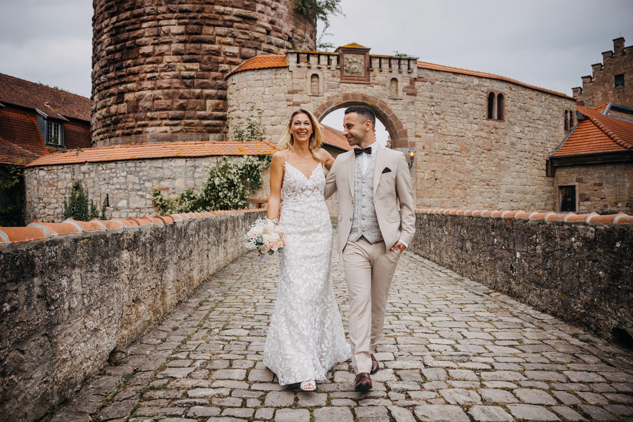 Ein Brautpaar auf einer historischen Steinbrücke, fotografiert von BKfotofilm – professionelle Hochzeitsfotografie und Hochzeitsfilme in Würzburg.