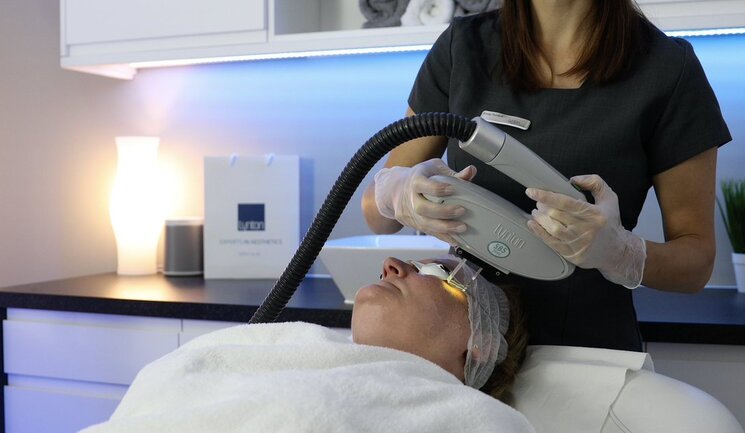 a woman laying on top of a bed holding a hair dryer