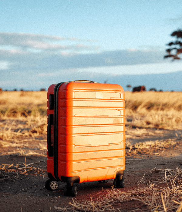 Orange suitcase on a dirt road, representing the ease of travel and the start of a Book Africa journey.