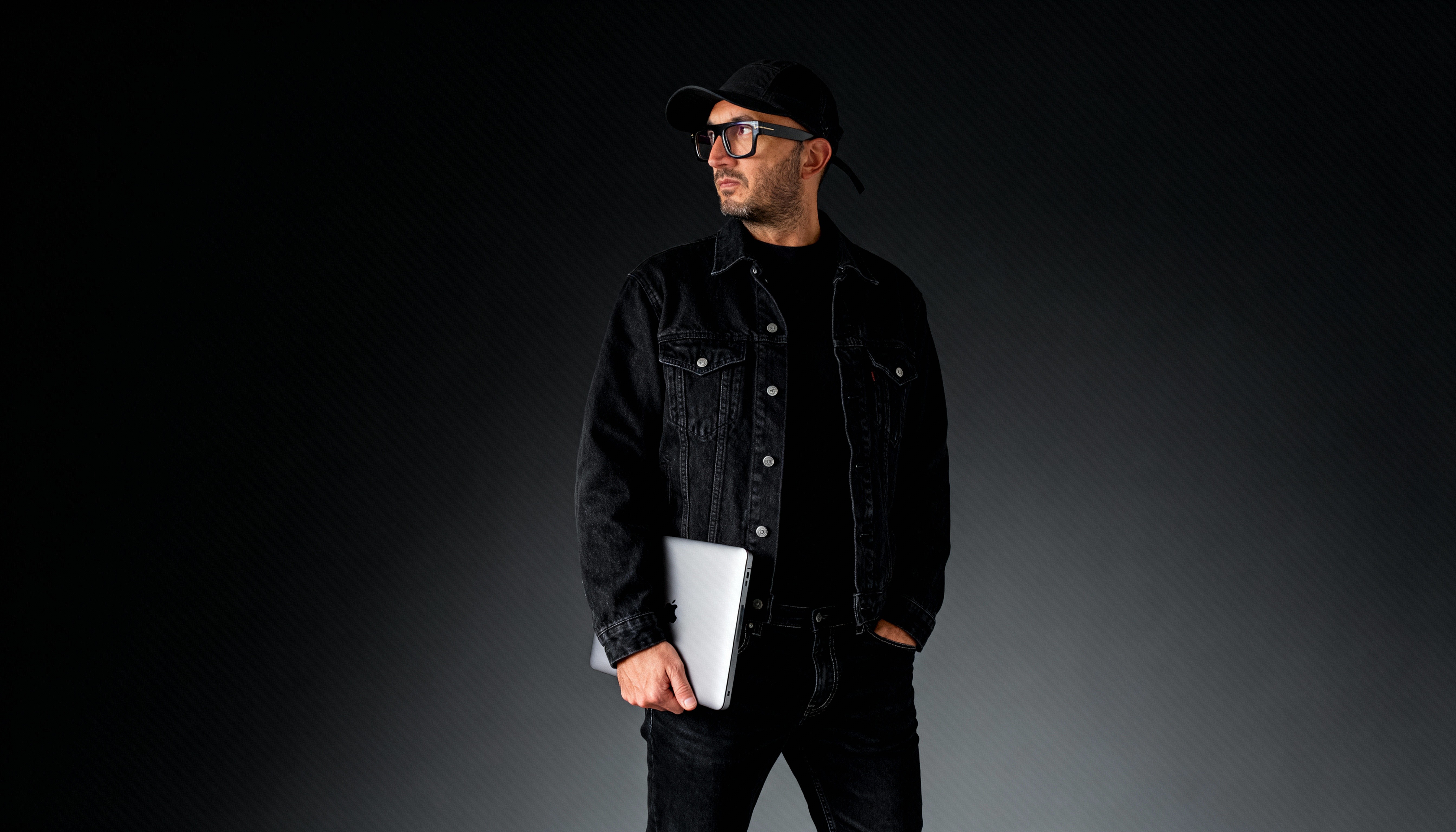 Black and white image of people working at a table with laptops, showing hands gesturing during discussion of digital content displayed on screens, with fabrica® logo in the corner.