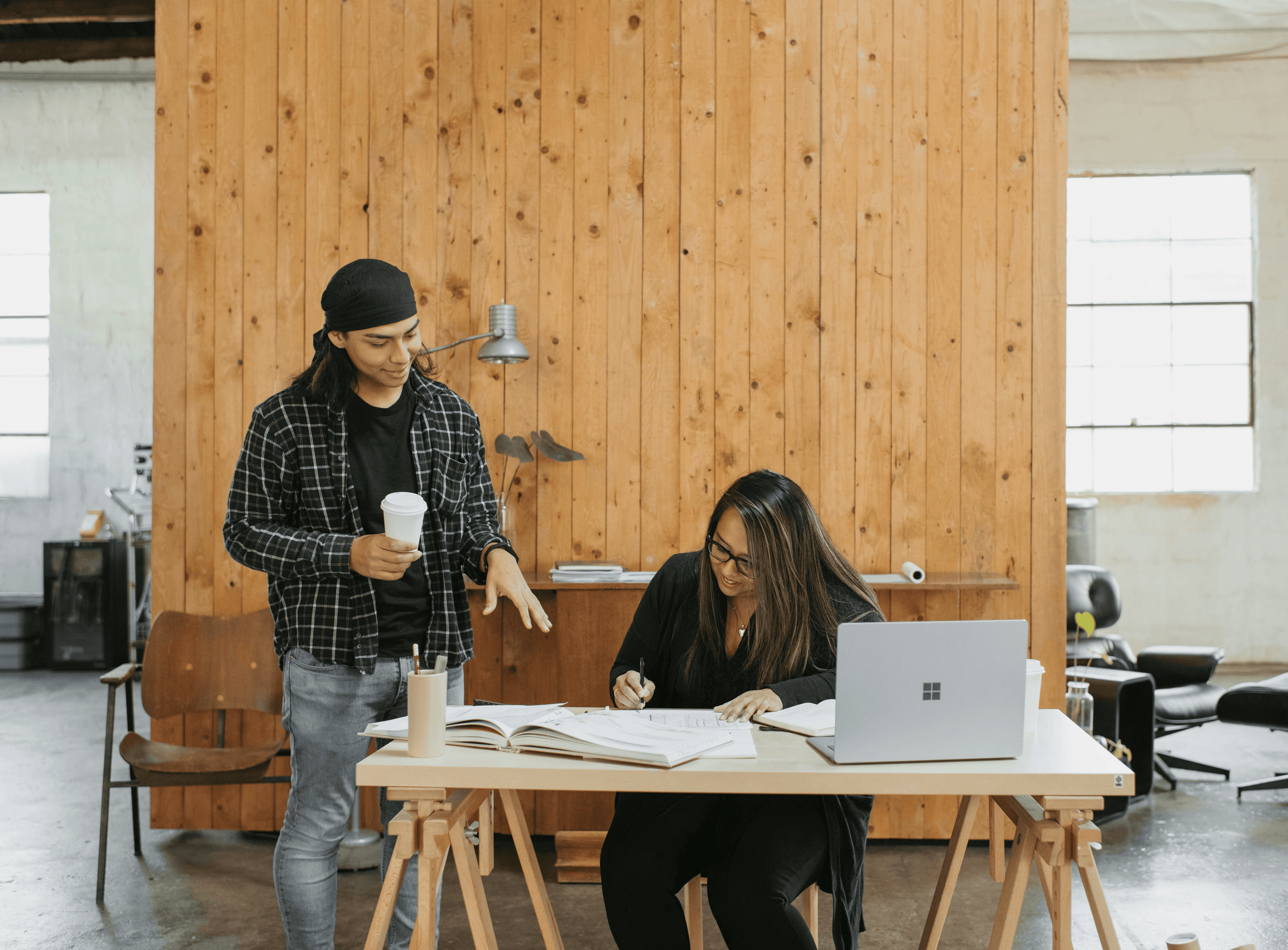 a man standing next to a woman working on a laptop