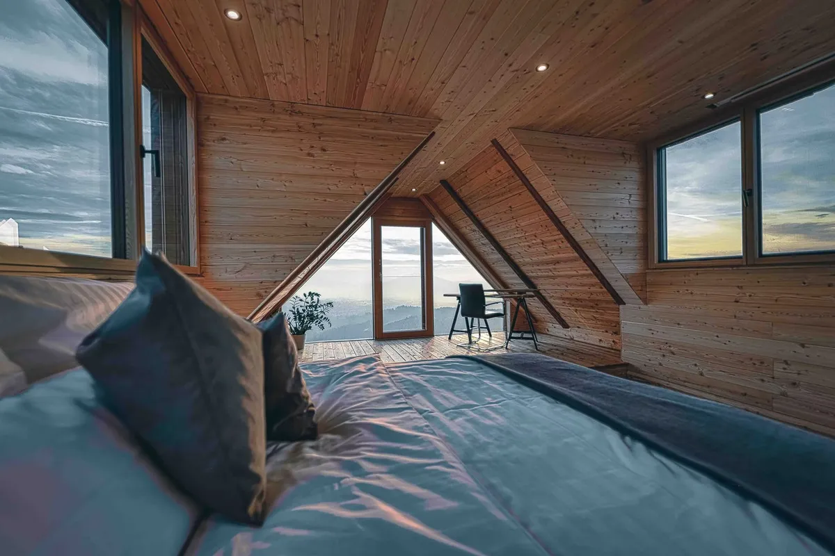 Schlafzimmer im Dachgeschoss mit Holzverkleidung, Eckfenstern und Arbeitsplatz in Weinitzen