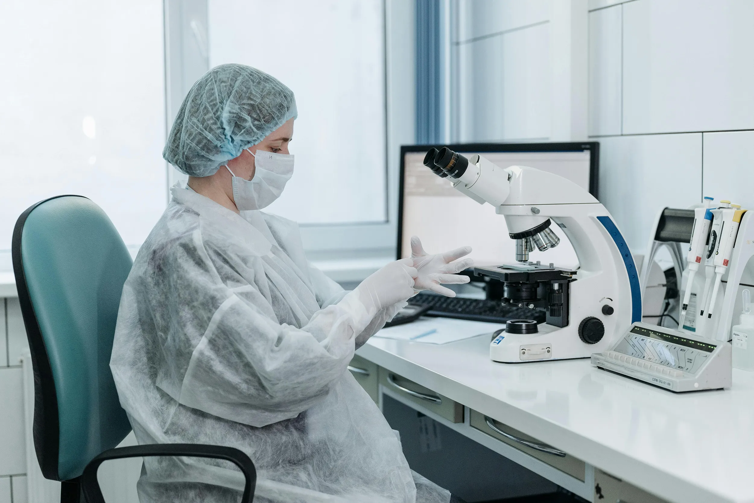 Medical laboratory technician working with microscope in sterile research environment