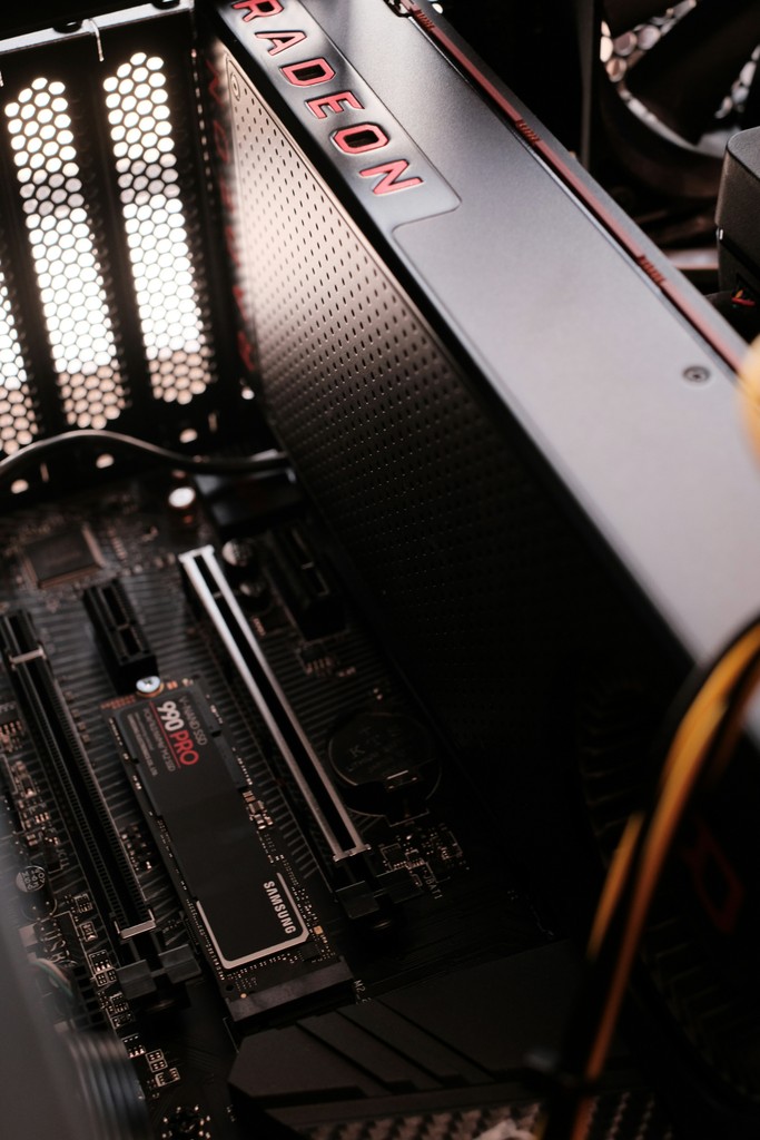 A close-up of a high-performance computer's interior, featuring an AMD Radeon graphics card and a Samsung 990 Pro SSD installed on the motherboard, highlighting advanced PC hardware components and gaming or computing power.