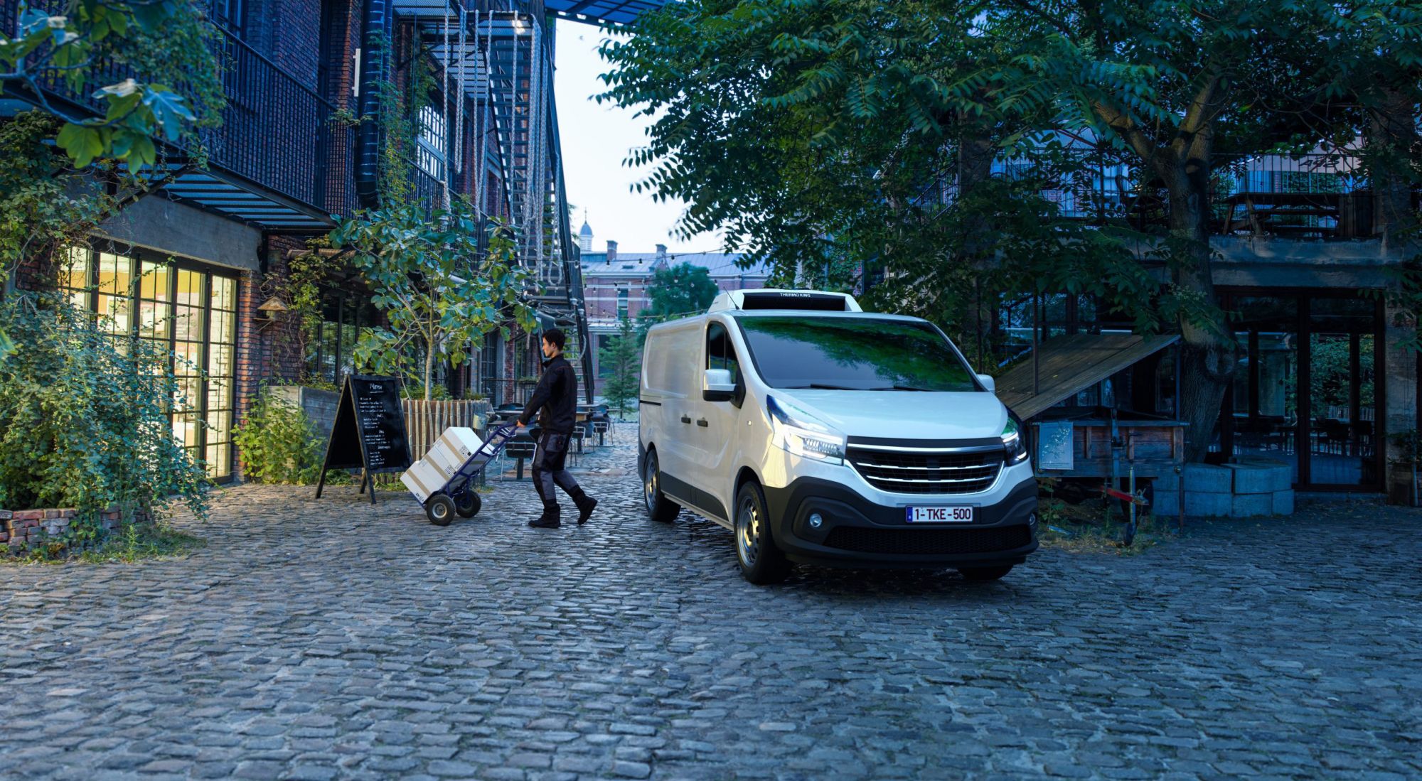 Ein weißer Van mit Thermoking E-500e parkt auf einer gepflasterten Straße.
