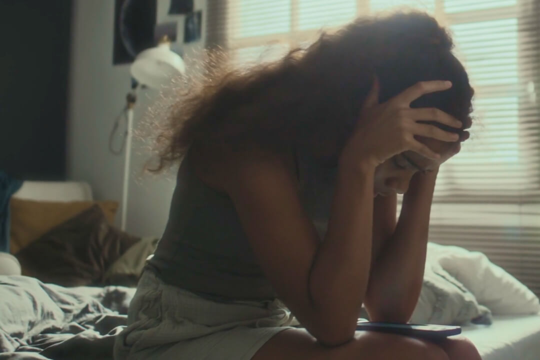 Teenager sitting on her bed stressed by apps on her smartphone