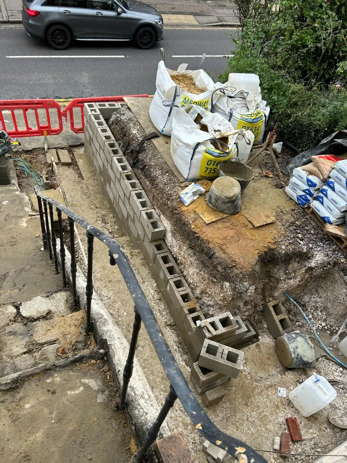 A view of a construction site showing materials piled on scaffolding, with a road and vehicles in the background.