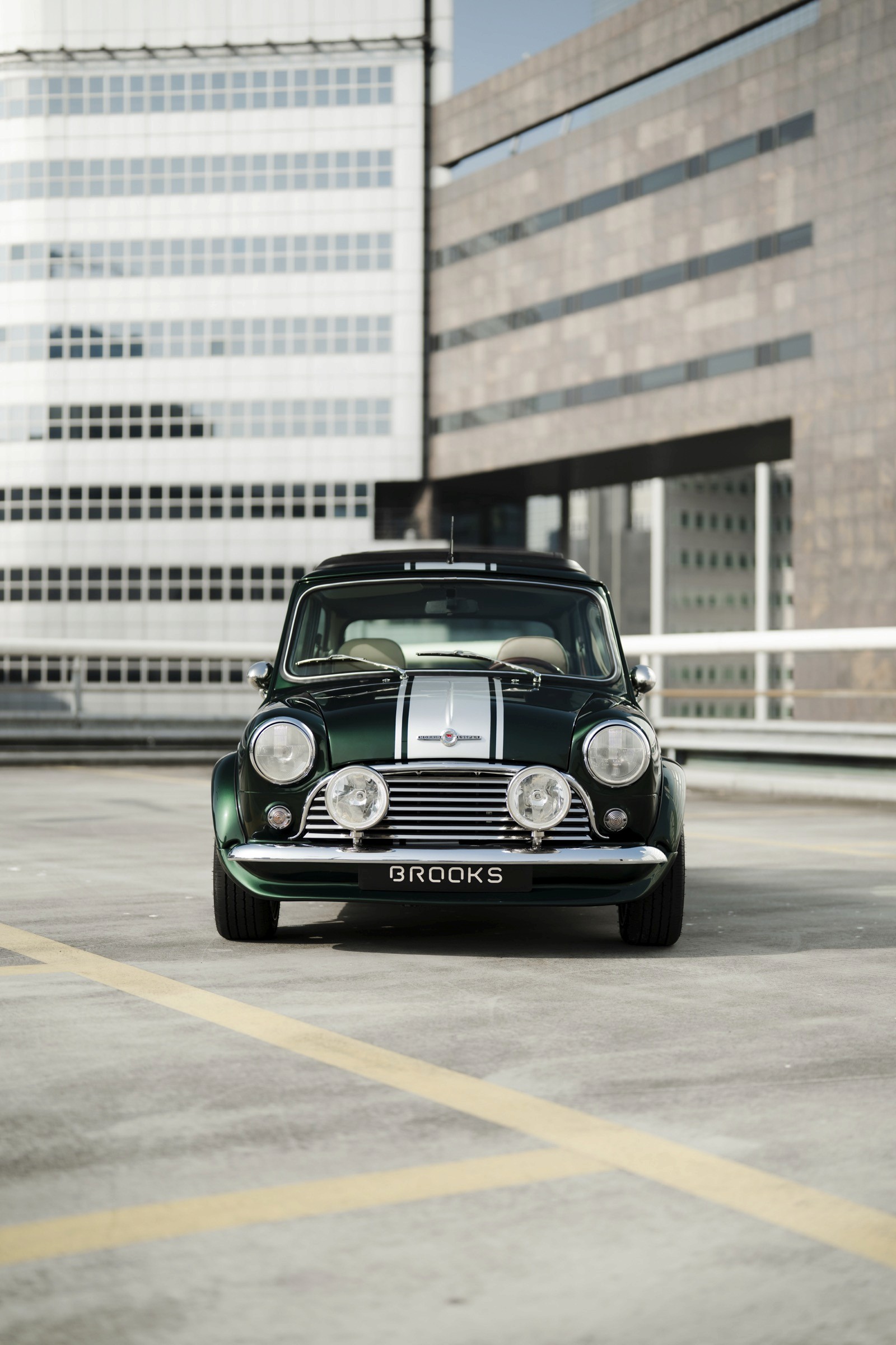 A classic black car parked in an urban setting, with modern buildings in the background.