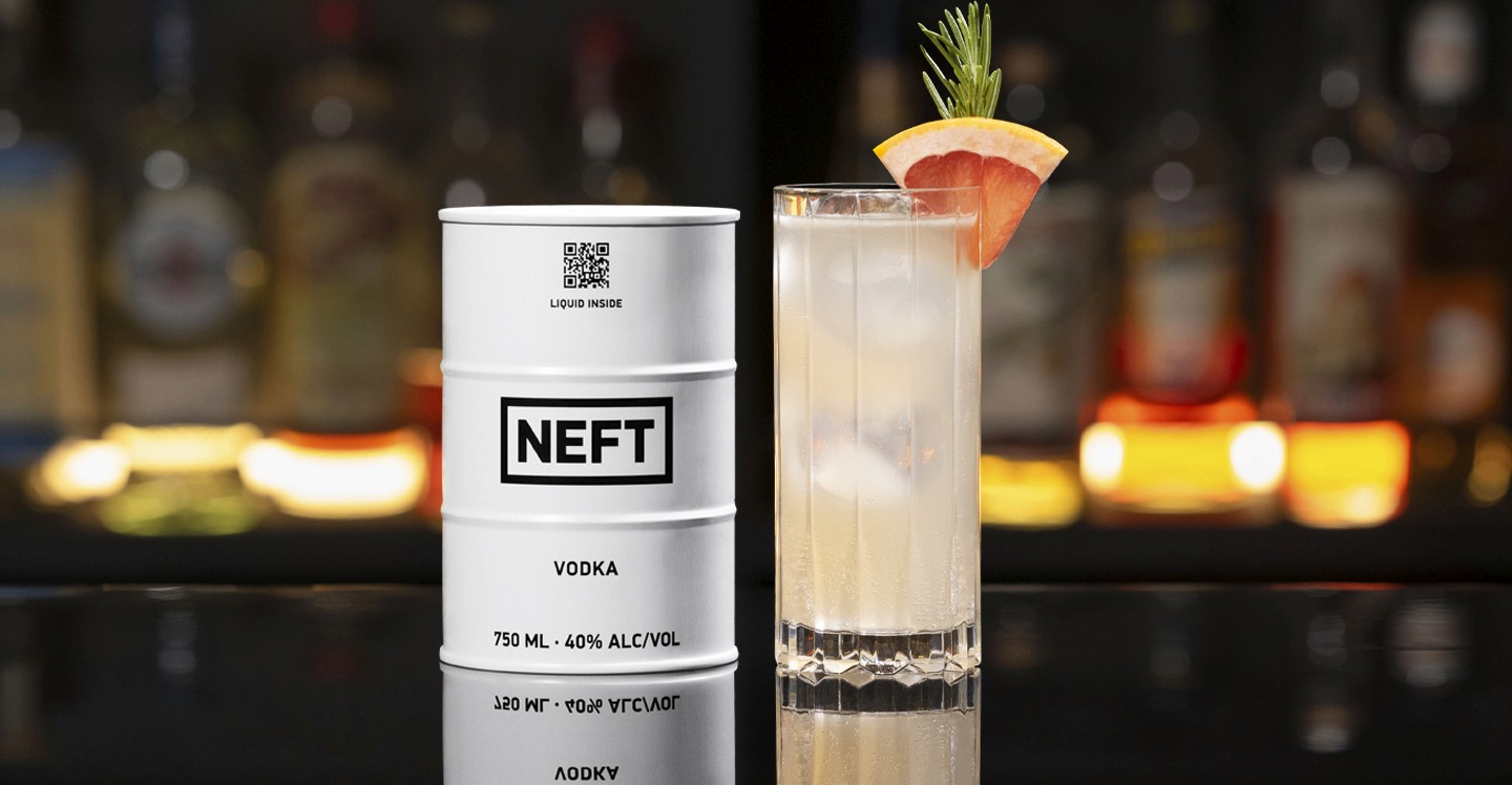 A NEFT Barrel and a glass of Halston on a bar counter.