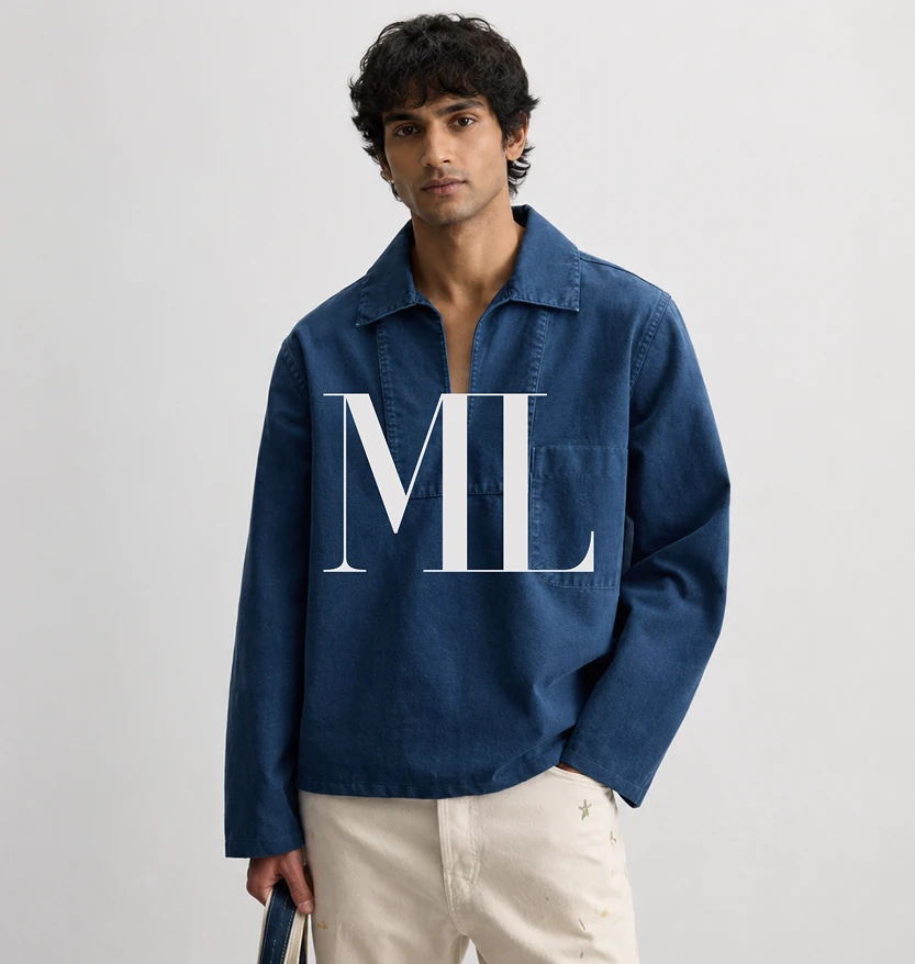 A young man in a blue denim overshirt and cream trousers with a large white "ML" monogram overlaid on his chest.