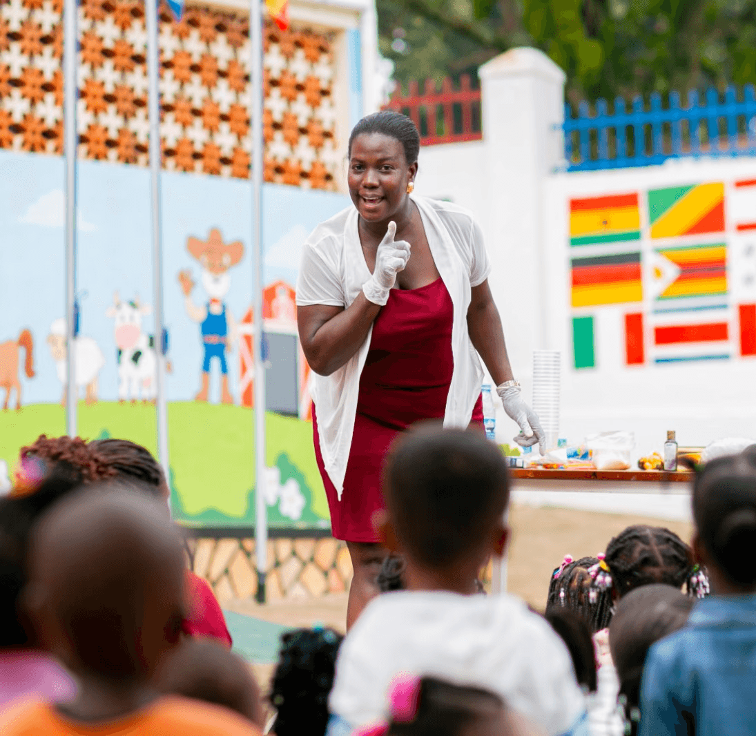 A student wearing a red uniform sits while holding a book in his hands