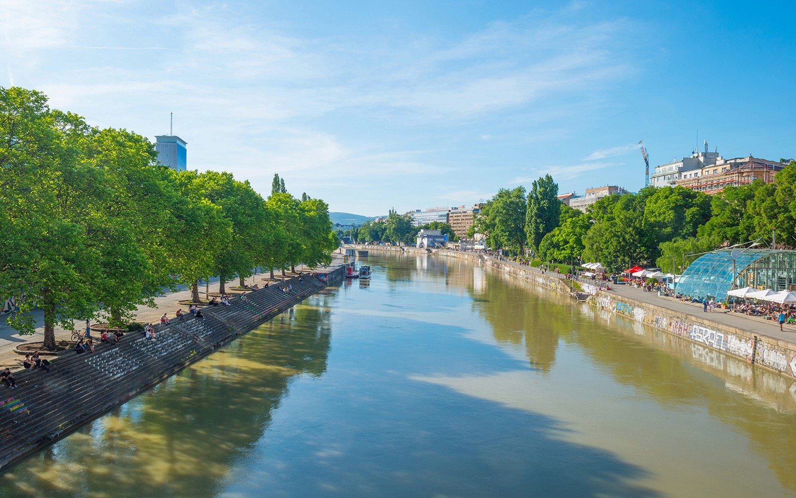 Donaukanal Danube Canal in Vienna, Austria, with people relaxing on the banks.