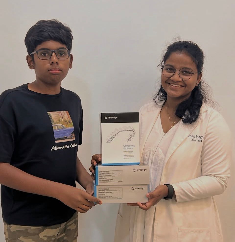 Smiling person in glasses outdoors with trees in background