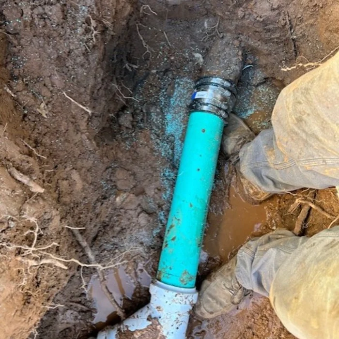 Excavator working beside large underground utility pipes