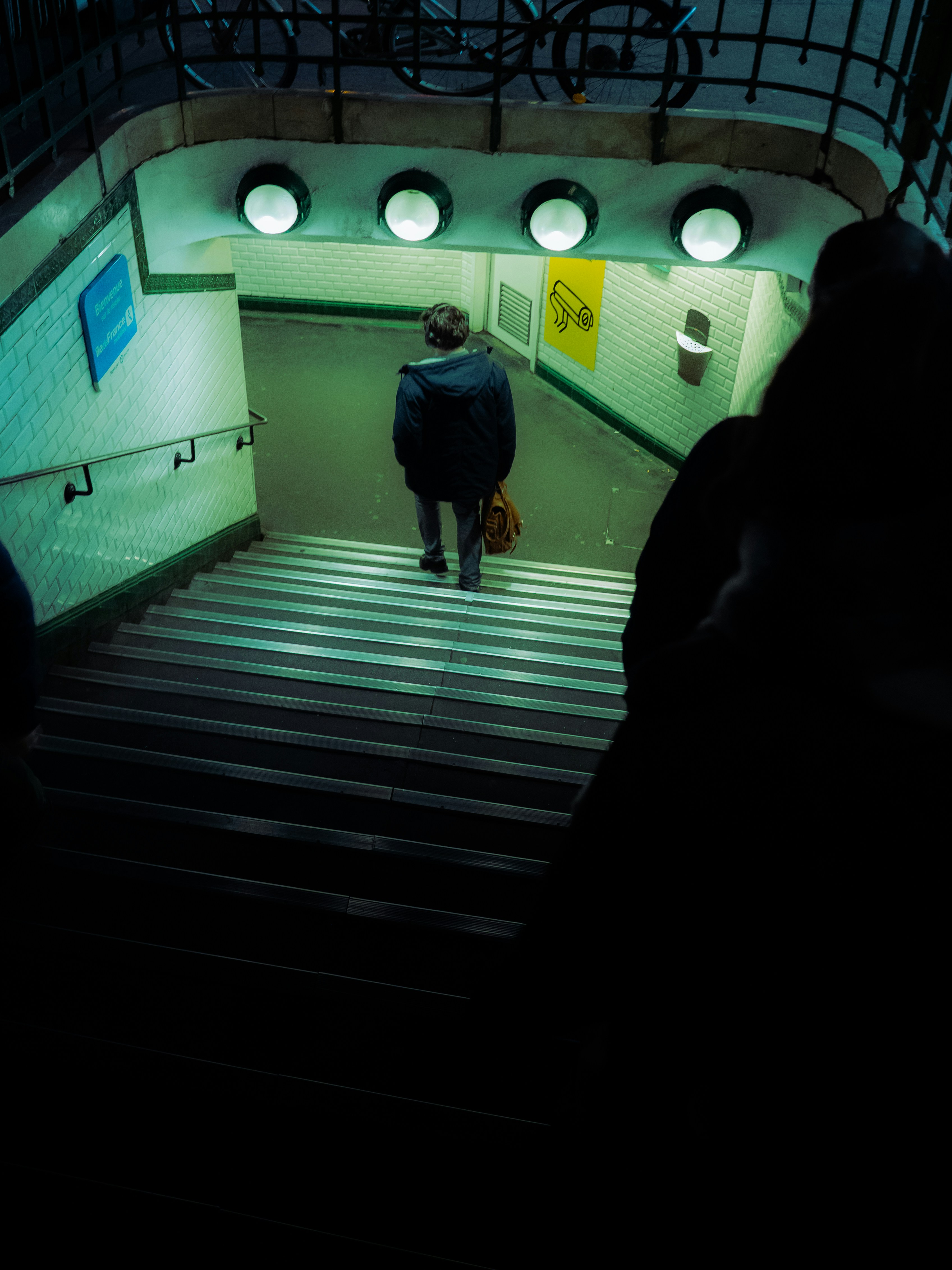 A person walks down subway stairs at night.