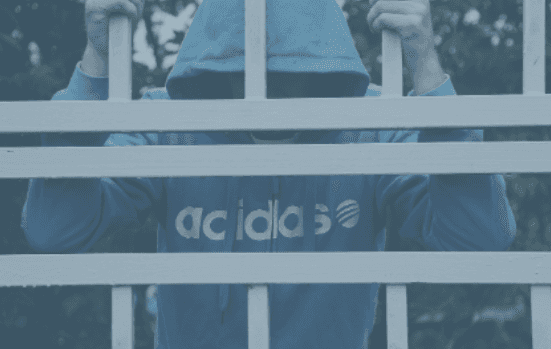 Man in blue jumper holding onto railings, being locked out of somewhere