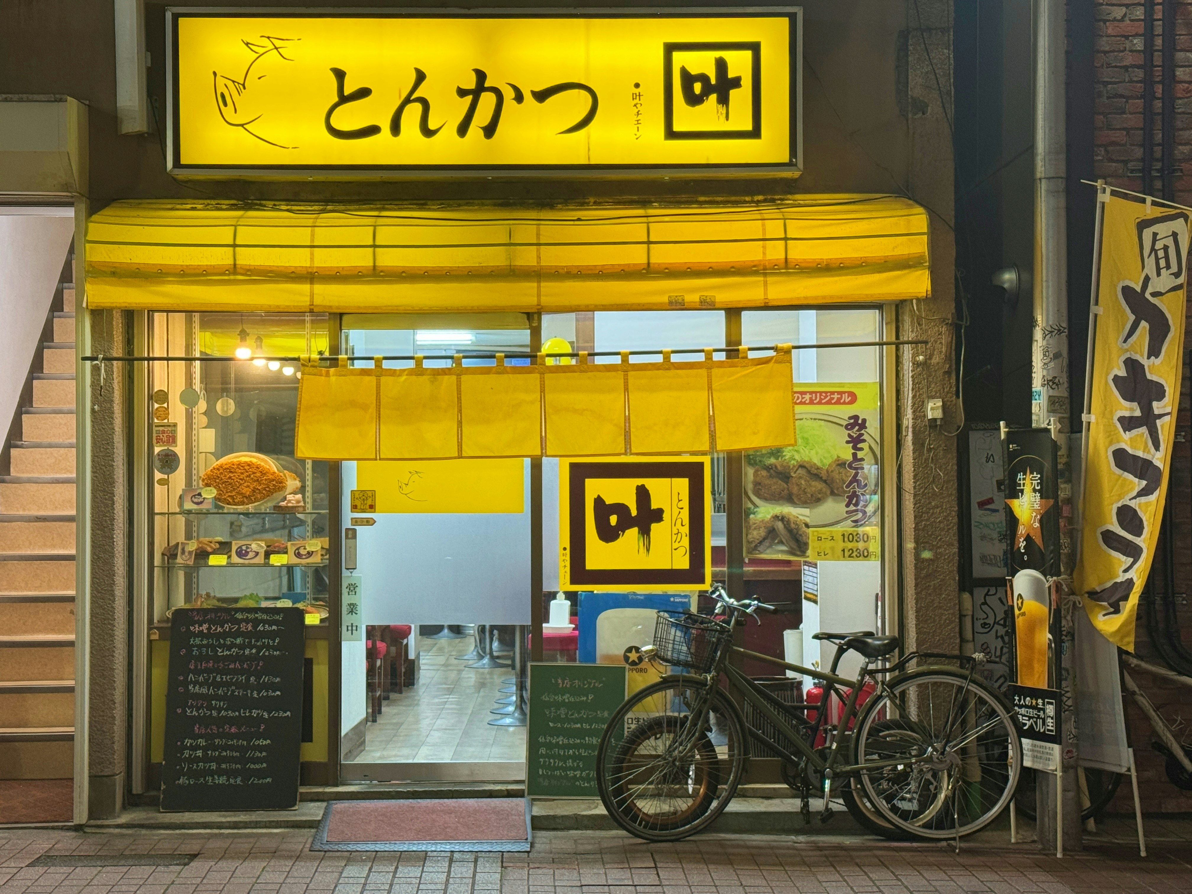 A yellow store front with bicycles parked outside of it