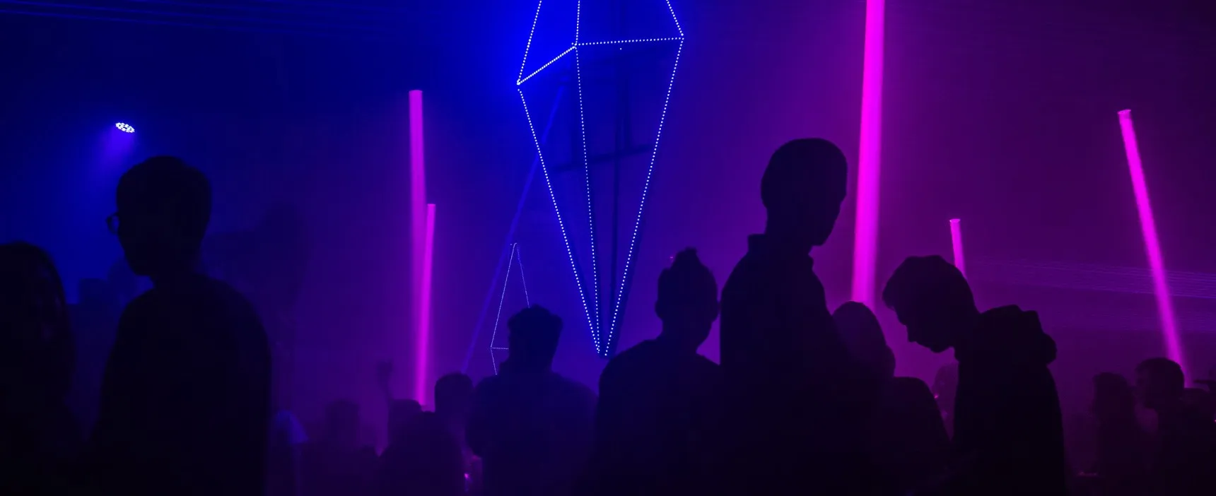 Crowd silhouetted against purple and blue dance-floor lights