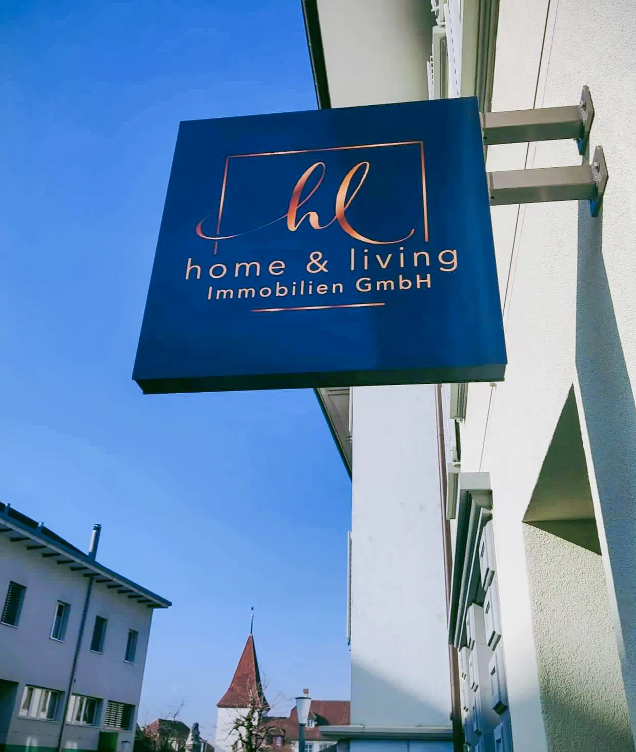 Firmenschild von home & living Immobilien GmbH vor dem Maklerbüro