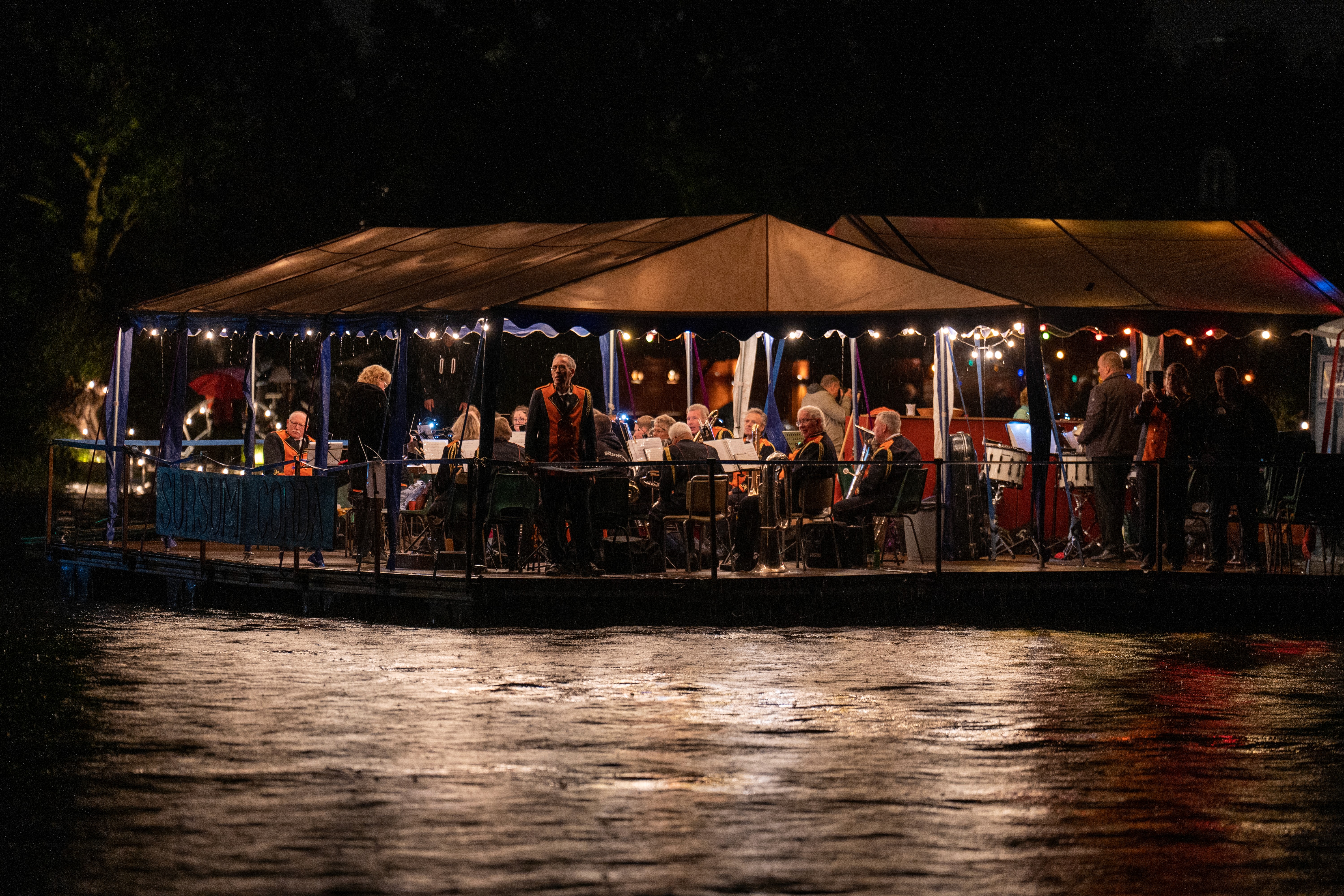 A volleyball player in a black uniform jumping high to spike the ball at the net while opponents attempt to block.
