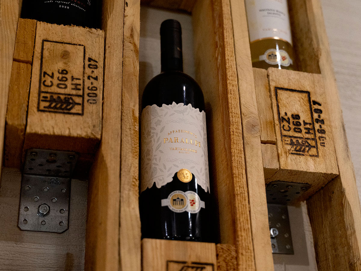 Sélection de vins exposée au Restaurant Miragem à Pétange, Luxembourg, mettant en avant une bouteille de vin raffiné dans un présentoir en bois rustique.