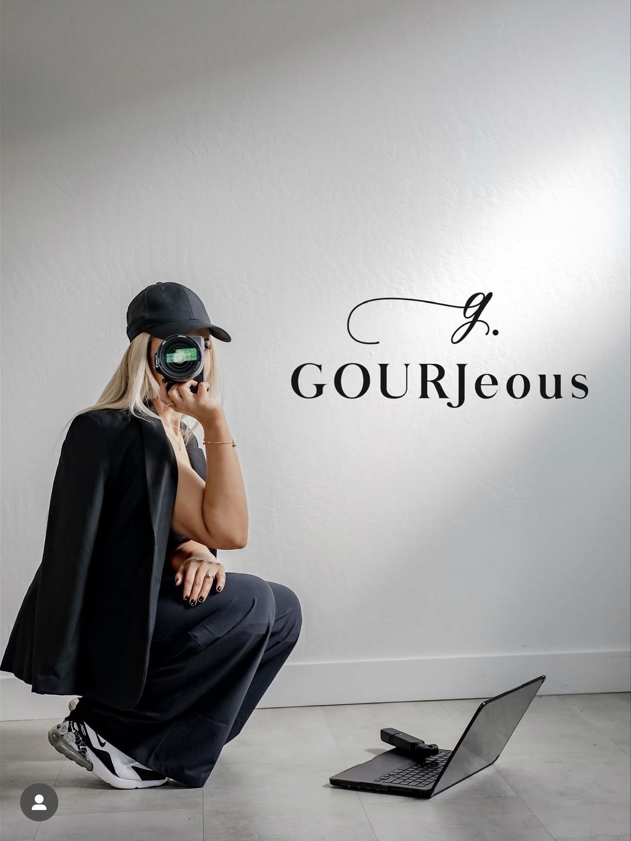 A person with short blonde hair holds a vintage camera.