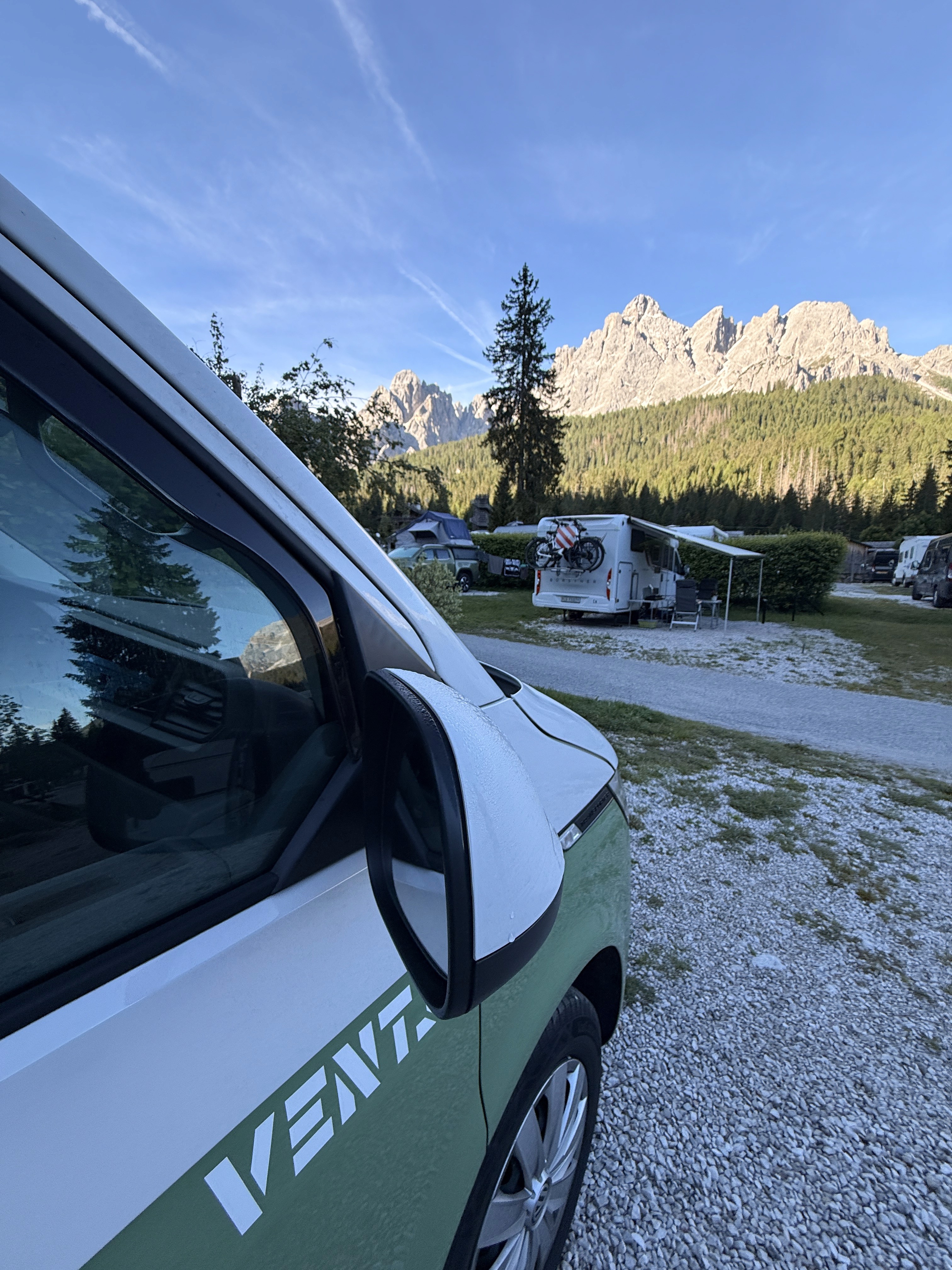 four wheel drive vehicle set up with a rooftop tent next to a lake at golden hour