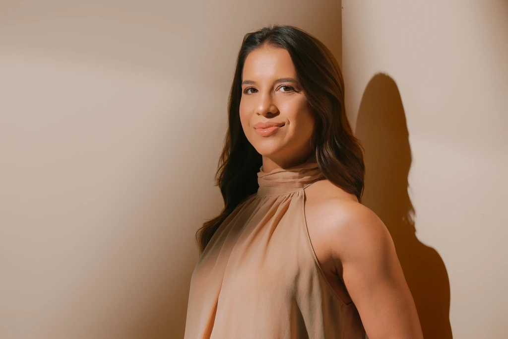 Isabela Ramos sorrindo de lado em ensaio profissional com vestido nude e iluminação dramática