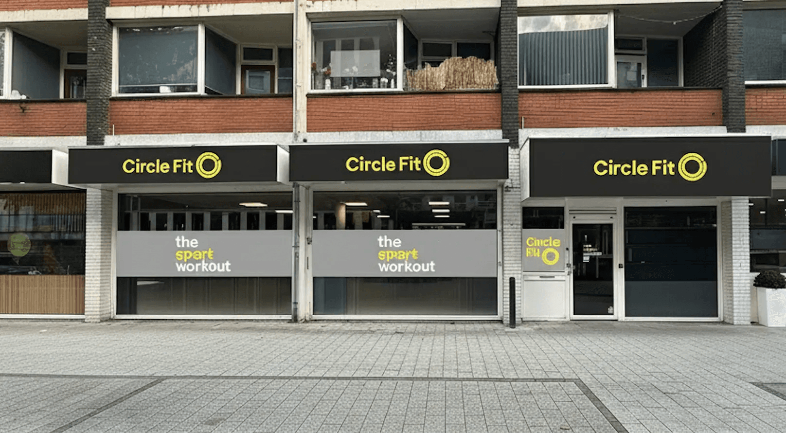 A brightly colored Circle Fit hub exterior with outdoor seating and a small cart on the sidewalk.