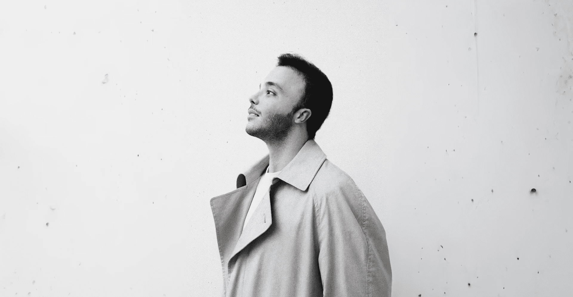 A silhouette of a person wearing sunglasses, with tousled hair, against a teal background.