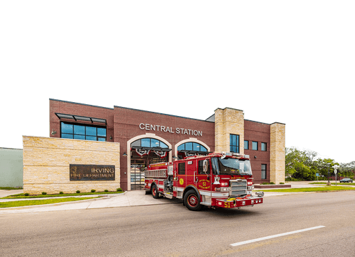 Brick and stone exterior of City of Irving Central Fire Station with Engine 51 and arched bay doors.