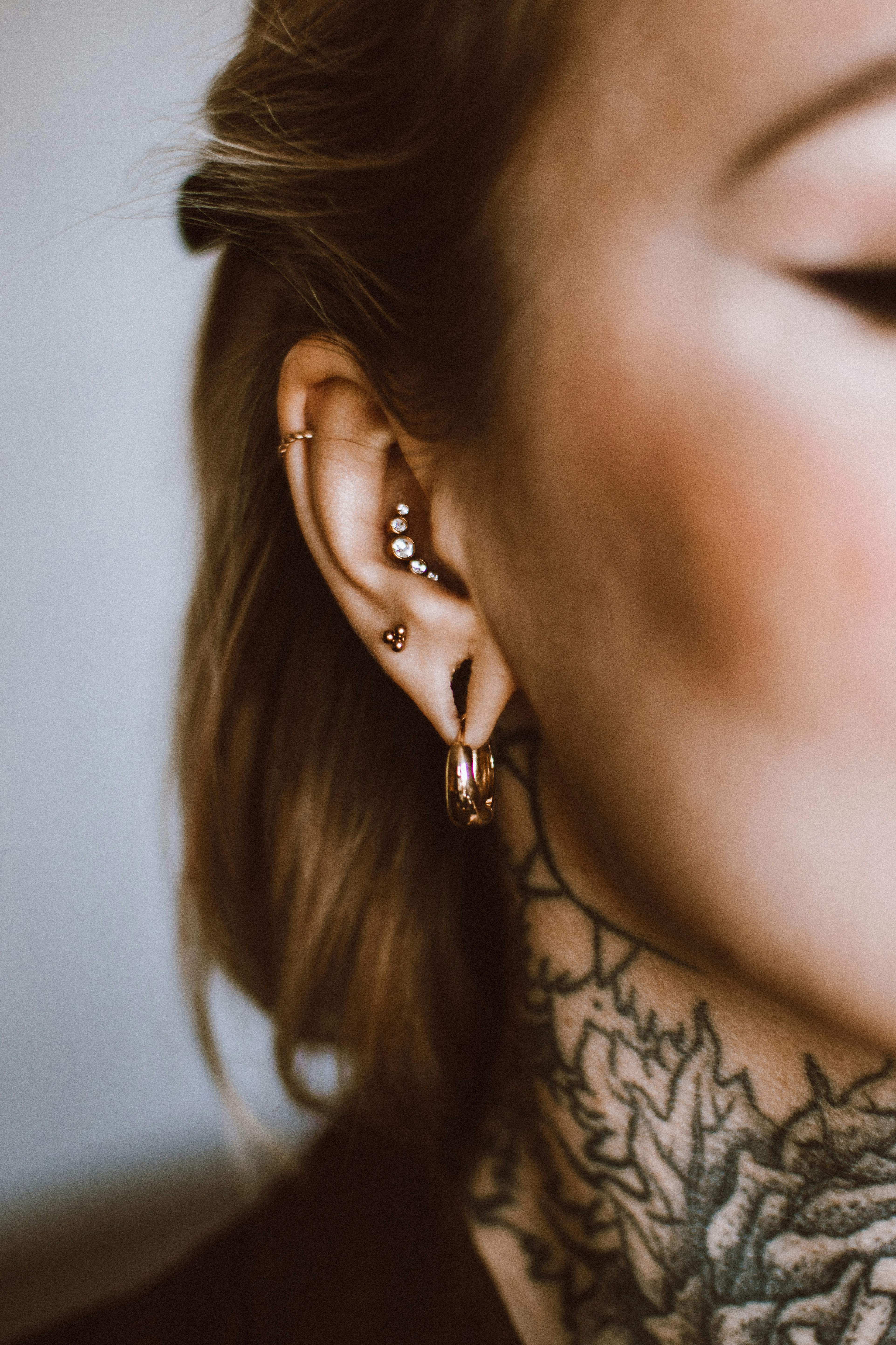 a woman with a tattoo on her neck and behind her ear