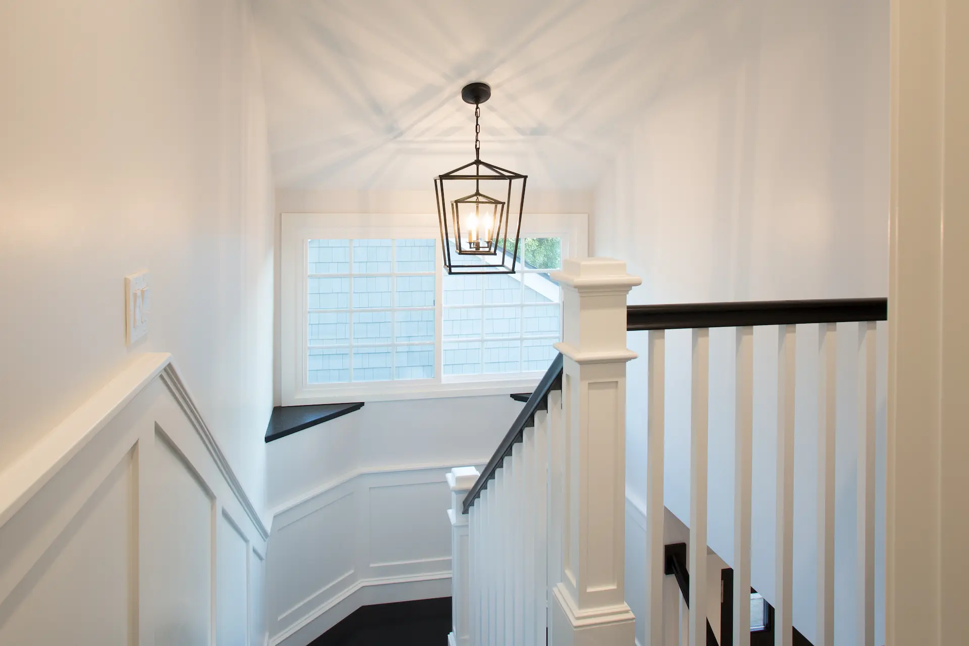 Bright stairwell with white balusters, dark handrails, elegant pendant light. From Dana Point Cape Cod remodel, photo by Chris Darnall.