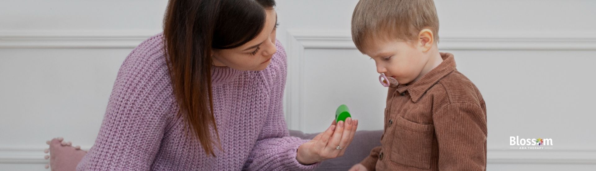 An ABA therapist and a young boy playing with wooden toys.