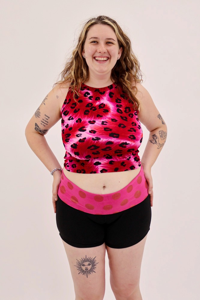 female model smiling, wearing leopard print pink tank